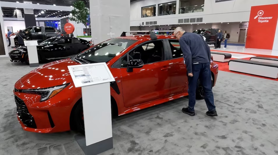 底特律车展媒体预览日期间，一名男子凝视着 2025 款丰田卡罗拉掀背车的车窗 ...